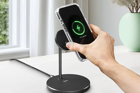 Mano sosteniendo un smartphone en un cargador magnético Qi2, con carga rápida inalámbrica activada.